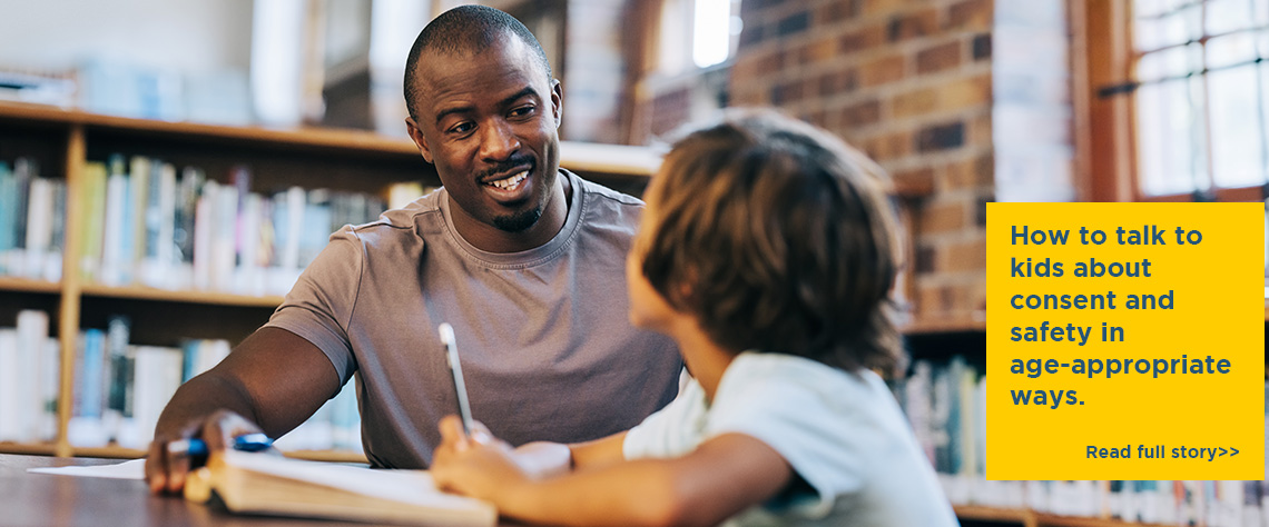 A man smiles as he talks to a young boy in a library or classroom. How to talk to kids about consent and safety in age-appropriate ways. Click to read full story.
